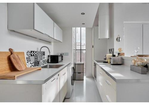 une cuisine blanche avec des armoires blanches et un évier dans l'établissement Duplex Center of Paris by Studio prestige, à Paris
