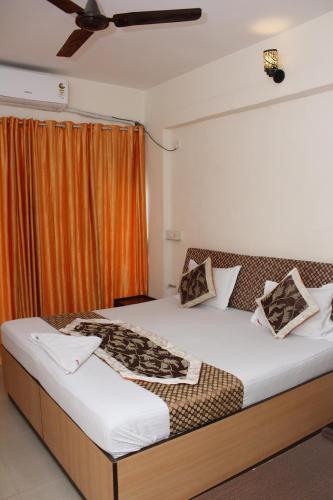 a bedroom with a large bed with an orange curtain at New Pinnacle Services in Ghansoli
