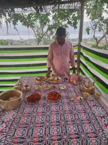 a man standing in front of a table with food at Jandyal Farm House in Malshej Ghat