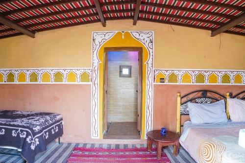 a bedroom with two beds and an open door at Sky Luxury Camp in Mhamid
