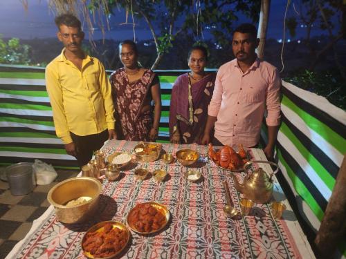 a group of people standing around a table with food at Jandyal Farm House in Malshej Ghat