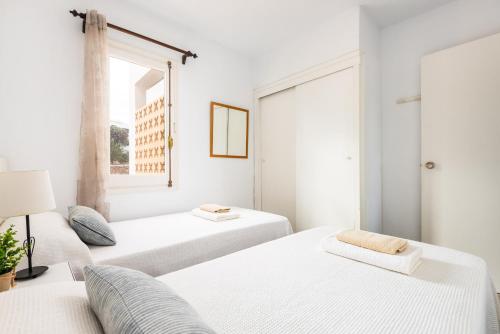 two beds in a white room with a window at Apartamento Els Pins by Escapehome in Punta Grossa