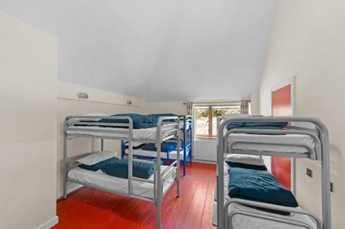 a room with three bunk beds and a window at Knockree Hostel in Enniskerry
