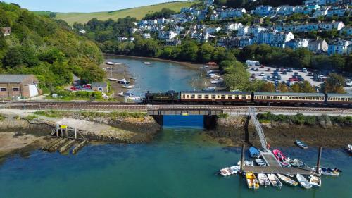 a train crossing a bridge over a river with boats at Large Riverside Retreat With Panoramic Dart Views in Dartmouth