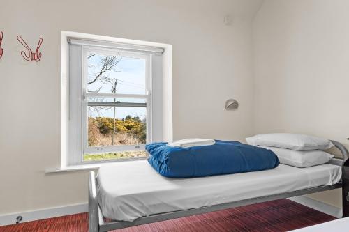 a bed with a blue pillow sitting next to a window at Knockree Hostel in Enniskerry