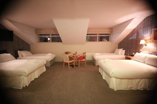 a room with four beds and a table in it at Mellon Country Inn Hotel in Omagh