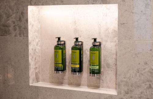 three green bottles sitting on a shelf in a wall at Dos Reis by The Beautique Hotels in Lisbon