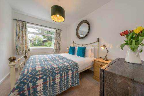 een slaapkamer met een bed en een vaas met bloemen bij Cae-Calch in Morfa Nefyn