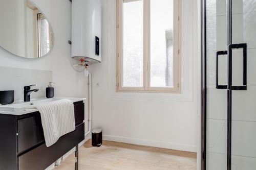 - une cuisine blanche avec un évier et un miroir dans l'établissement Élégance et confort en plein cœur de Saint-Étienne, à Saint-Étienne