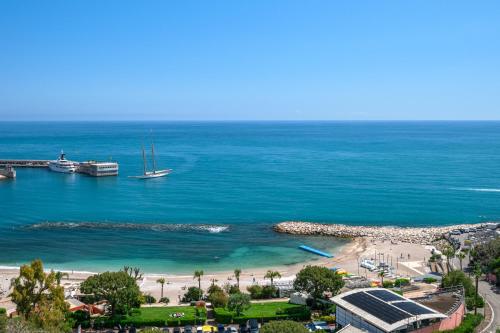a view of a beach with a boat in the water at Panorama Mer et Plage Cap d Ail proche Monaco in Cap d'Ail