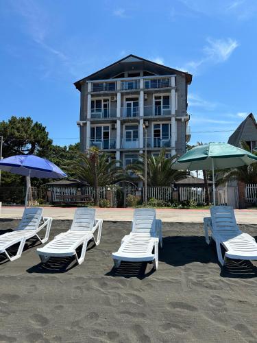 a group of lounge chairs and umbrellas on a beach at Hotel George in Ureki