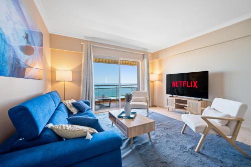 a living room with a blue couch and a tv at Panorama Mer et Plage Cap d Ail proche Monaco in Cap d'Ail