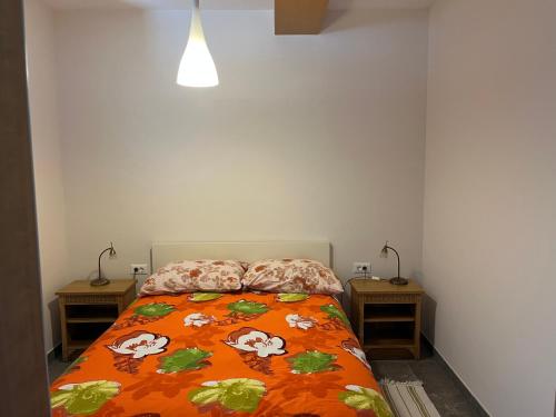 a bedroom with a bed with an orange comforter and two tables at Počitniška hiša Pri Kuštrču in Grahovo