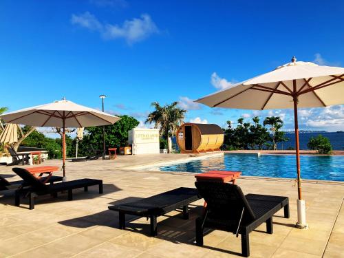 a pool with chairs and umbrellas next to a swimming pool at LiVEMAX Amms Canna Resort Villa in Ginoza