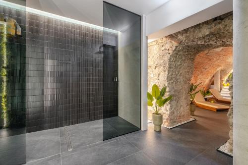 a glass shower in a bathroom with a stone wall at Muse - LoftAffair Spa Collection in Kraków