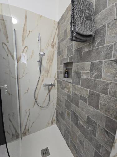 a bathroom with a shower with a stone wall at Casa vacanze Le cicale in Pesaro