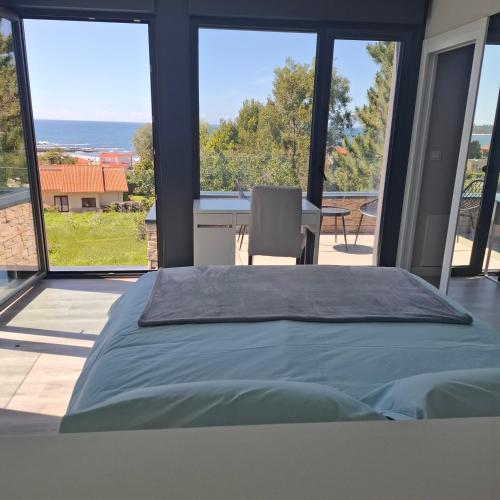 a bedroom with a bed and large glass windows at Chalet de lujo con piscina cercano a la playa in Nigrán