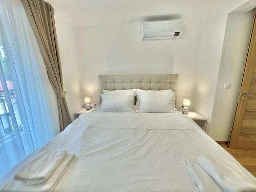 a bedroom with a large white bed with two lamps at Luxury Apartments Przno in Budva