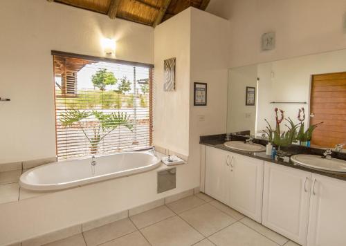 a bathroom with two sinks and a tub and a window at Mount Savannah Lodge by Dream Resorts in Krugersdorp