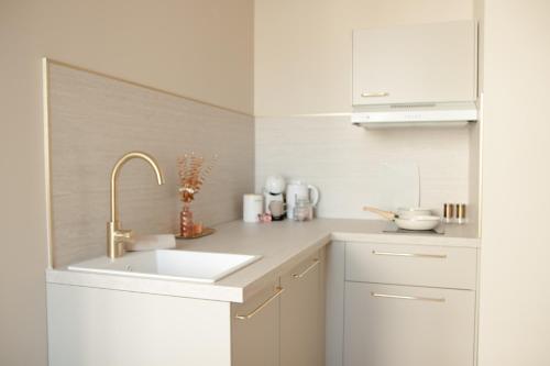 une cuisine avec des armoires blanches et un évier dans l'établissement Studio meublé Le Refuge doré avec Netflix, à Homécourt