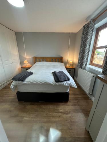 a bedroom with a bed and two lamps on two tables at Honeybee Cottage in Lincolnshire