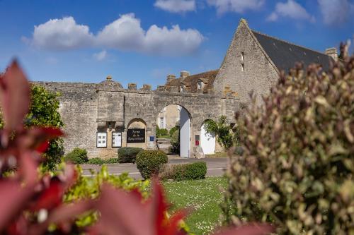 an old stone building with an archway in a yard at Ferme de la Rançonnière - Hôtel & Restaurant in Crépon