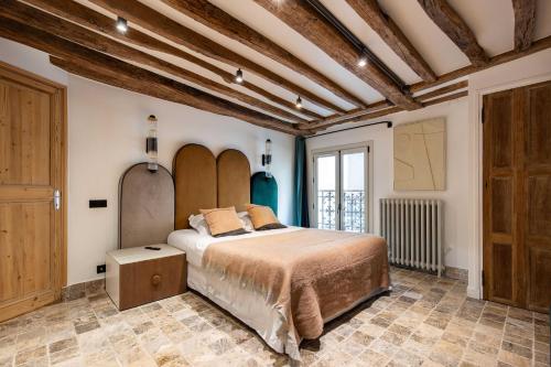 une chambre avec un lit dans une pièce avec des plafonds en bois dans l'établissement CMG Amazing Duplex 3BR 6P Le Marais, à Paris