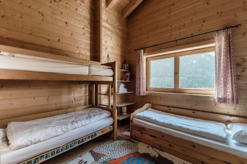 two bunk beds in a log cabin with a window at Chalet Dalpe by Quokka 360 - chalet among pastures and forests in Dalpe