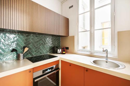 une cuisine avec des armoires orange et un évier ainsi qu'une fenêtre dans l'établissement Charm and Elegance for 8P-3BR - Grands Boulevards, à Paris