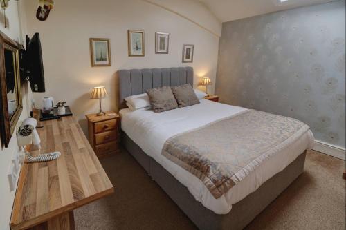 a bedroom with a large bed and a television at Ye Olde Cheshire Cheese Inn in Castleton
