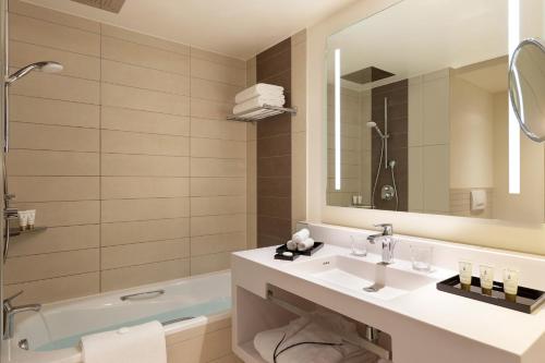 a bathroom with a sink and a tub and a mirror at Pullman Paris Centre - Bercy in Paris