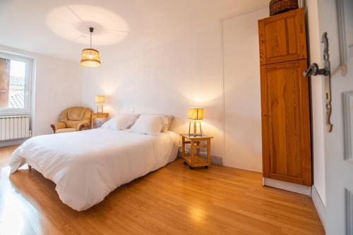 une chambre avec un grand lit blanc et une chaise dans l'établissement Standing apartment with terrace for 6 people - LE MAZAGRAN - appartement 2, à Saint-Paul-Trois-Châteaux