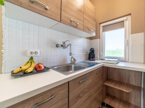 una cucina con un lavandino e frutta su un vassoio di Salix Guesthouse by Mital a Szeged