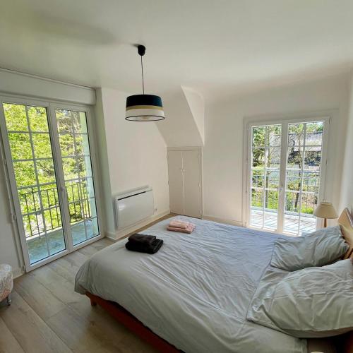 een slaapkamer met een groot bed en twee ramen bij Détente à la mer Blanche in Fouesnant