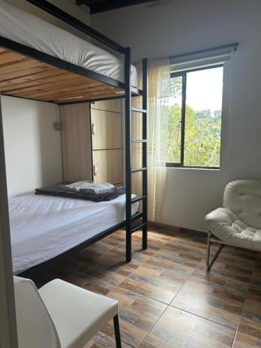 a bedroom with two bunk beds and a chair at Tahiti Casa Campestre in Santa Bárbara