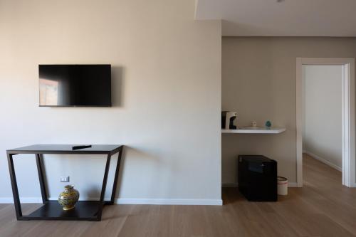 a living room with a table with a television on a wall at Le Absidi luxury rooms and suites in Sciacca