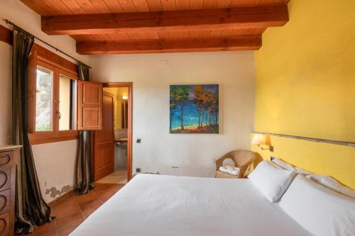 a bedroom with a white bed and a yellow wall at La Serreta in Gironella