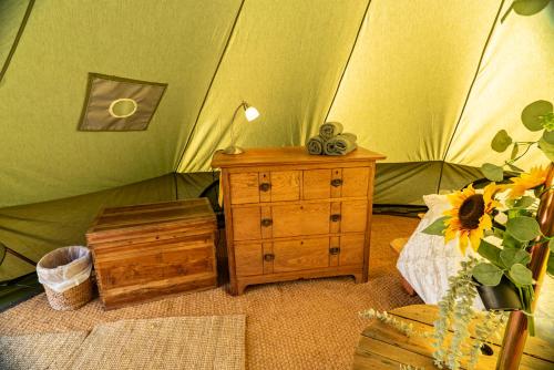 a bedroom with a green tent with a wooden dresser at Bluebell bell tent The Roaches in Upper Hulme