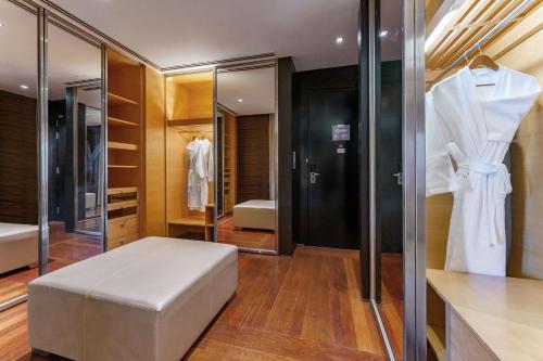 a dressing room with a white ottoman and a closet at Hilton Kuala Lumpur in Kuala Lumpur