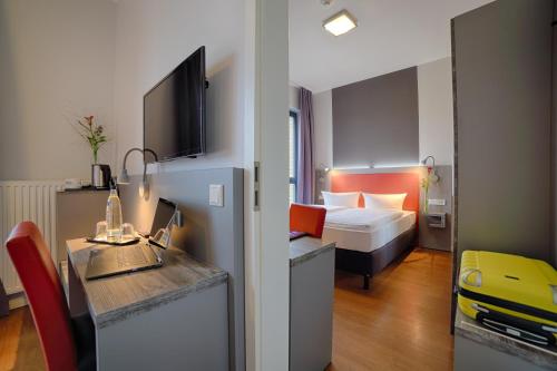 a hotel room with a bedroom with a bed and a desk at H+ Hotel 4Youth in Berlin