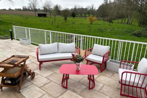 a patio with four chairs and a table with a vase at Gîte proche côte Granit Rose Paimpol Chants marins in Brélidy