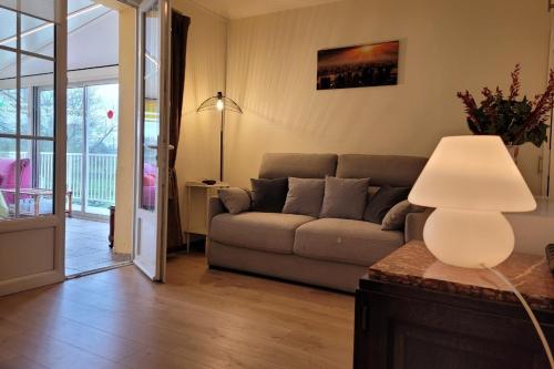 a living room with a couch and a lamp at Gîte proche côte Granit Rose Paimpol Chants marins in Brélidy
