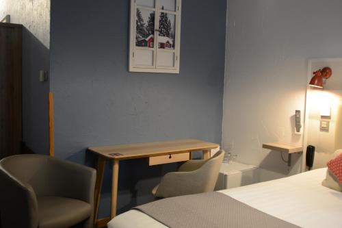 a room with a bed and a desk and a chair at Hotel SPA Au Cheval Blanc in Ribeauvillé