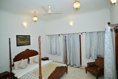 a bedroom with a canopy bed and a chair at Idar Haveli in Jodhpur