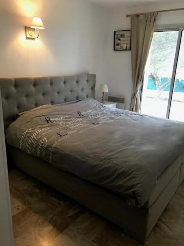 un lit dans une chambre avec une grande fenêtre dans l'établissement Jardin d’Uzès - Climatisée avec piscine, à Saint-Quentin-la-Poterie