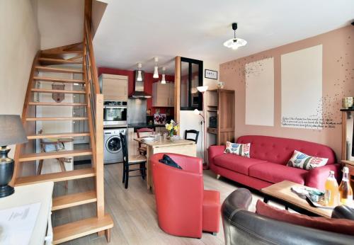 un salon avec un canapé rouge et une cuisine dans l'établissement Maisonnette Les Agapanthes de Cancale 23 personne, à Cancale