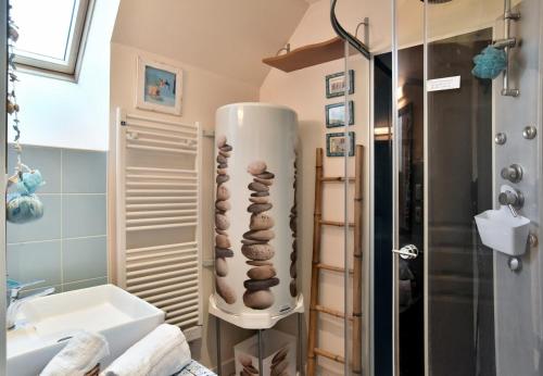 une salle de bain avec un lavabo et une douche avec des pierres dans l'établissement Maisonnette Les Agapanthes de Cancale 23 personne, à Cancale