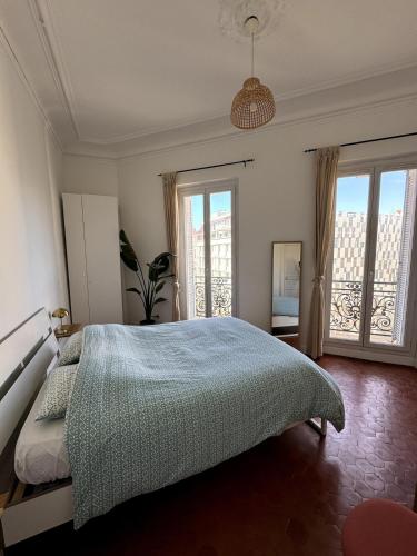 une chambre avec un lit et deux grandes fenêtres dans l'établissement Haussmannien - Lumière et mer, à Marseille