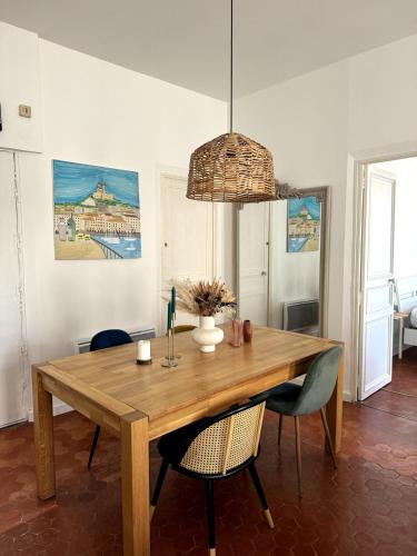 une salle à manger avec une table et des chaises en bois dans l'établissement Haussmannien - Lumière et mer, à Marseille