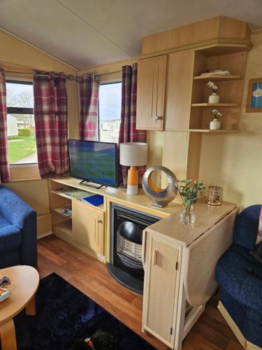 a living room with a desk with a tv and a couch at Daisy Lodge Lilac Grove 3 in Waxholme